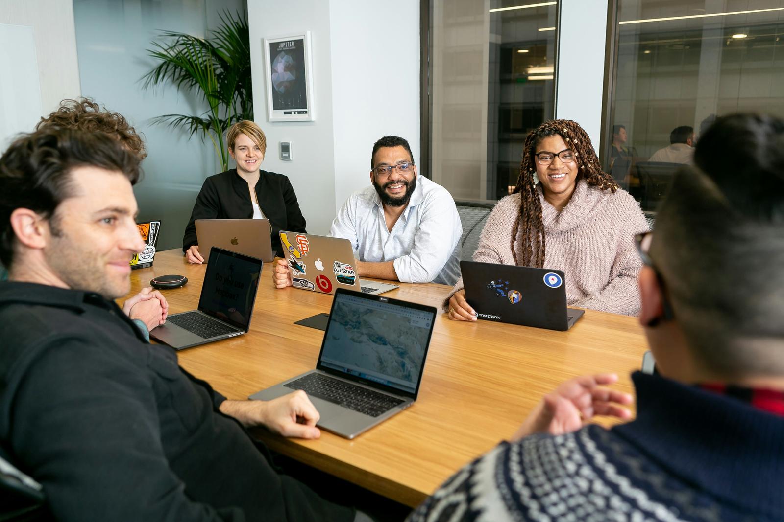 A small group talking around a table with laptops open.